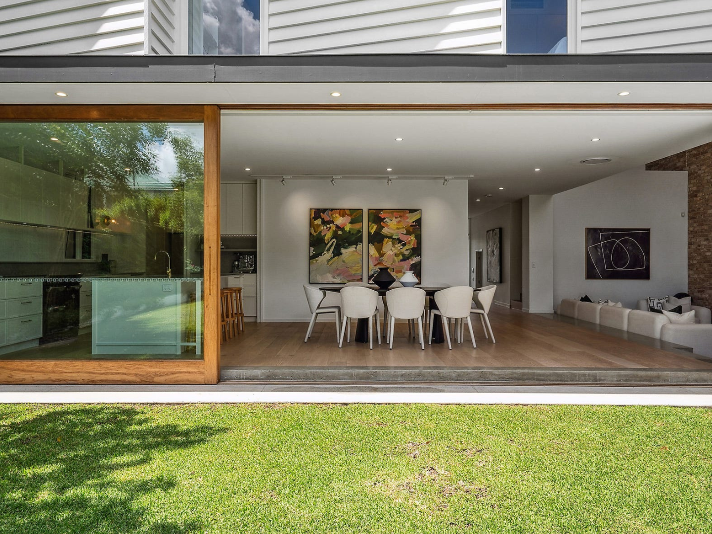 Dining room styled with contemporary artwork for hire with green grass in backyard in Brisbane home