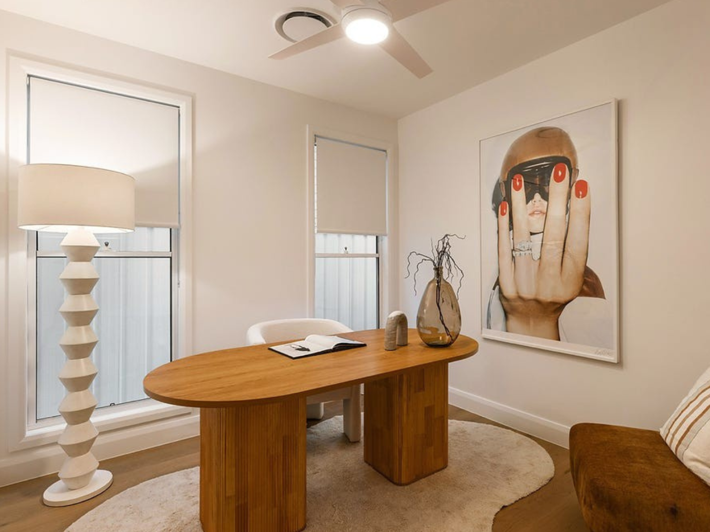 Modern home office with wooden desk, lamp, and artwork  for hire used as stylling on the wall.